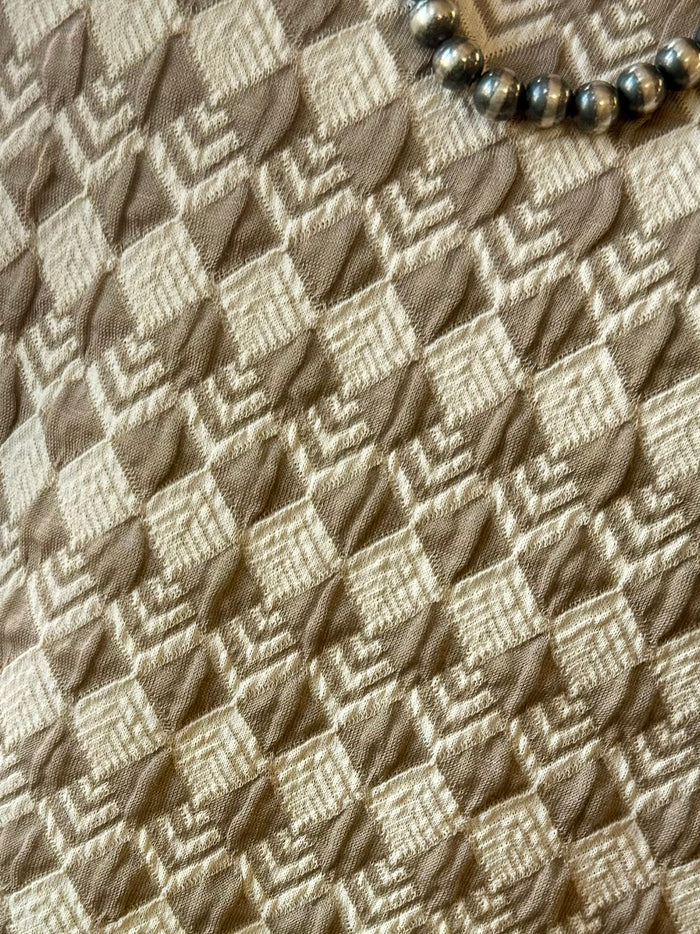 Tan geometric fabric close-up with repeating diamond grid texture