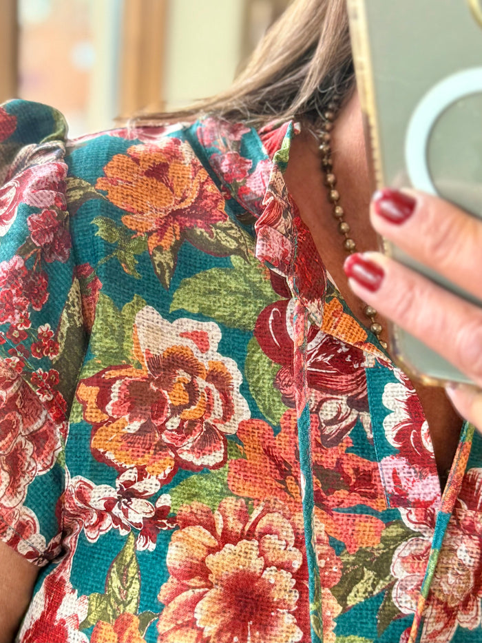 Multicolor floral flutter sleeve shirt on teal ground, buttoned V-neck