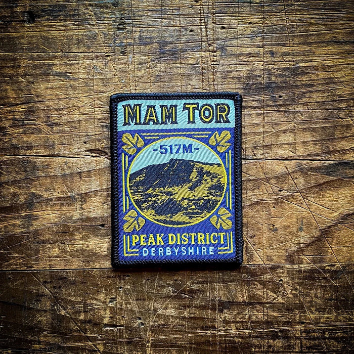 Forager Provisions LTD Mam Tor embroidered patch featuring a mountain landscape design on a rustic wooden background.