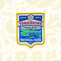 Yorkshire Dales National Park patch by The Adventure Patch Company on rustic scratched wood—collectible travel souvenir badge.