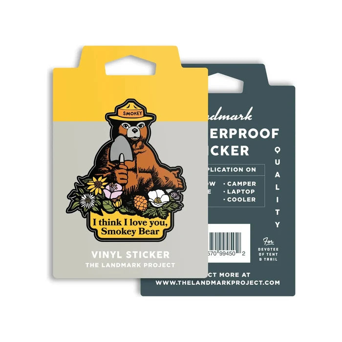 Illustration of Smokey Bear holding a shovel, surrounded by flowers with the text "I think I love you, Smokey Bear" at the bottom. This charming artwork is printed on weatherproof vinyl under the name "The Landmark Project I Think I Love You Smokey Bear Sticker" to support Wildfire Prevention Education.