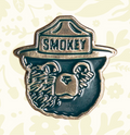 Smokey Bear enamel pin by Landmark Project shows Smokey’s face and ranger hat—perfect collectible for Smokey Bear fans.