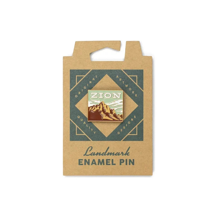 The Landmark Project Zion Pin is an enamel pin featuring a mountain landscape, attached to a cardboard backing with the text "Landmark Enamel Pin" and packaged sustainably.