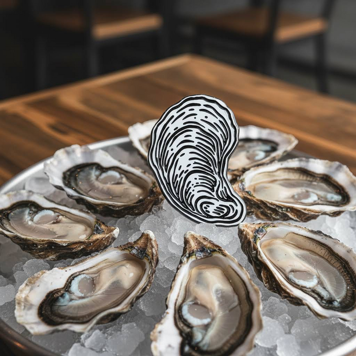 Forager Provisions LTD oyster enamel pin featuring a black and white shell illustration displayed on a bed of ice.