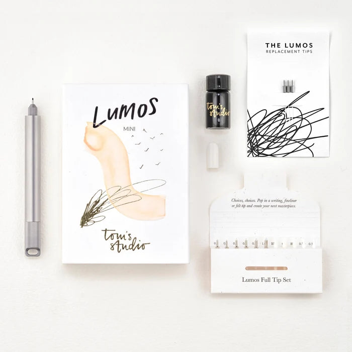 Tom’s Studio Lumos Mini Titanium pen, ink, tips & refill set neatly displayed on a white background. Luxury stationery kit.
