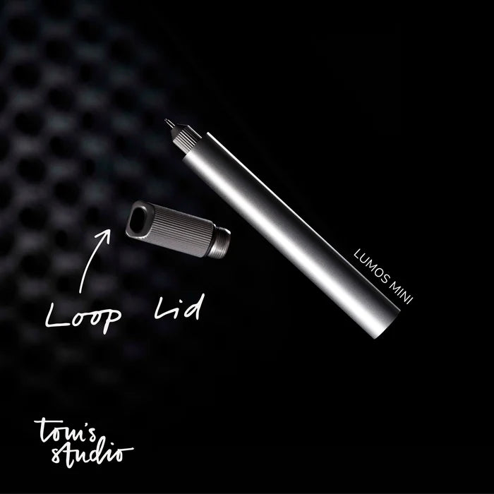 Tom’s Studio Lumos Mini Titanium pen with Loop Lid, sleek design for everyday writing, shown on a dark background.