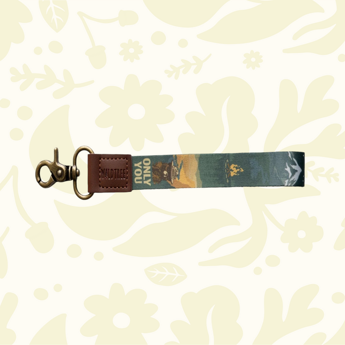Wildtree Smokey Bear keychain—leather/fabric, clasp, camera charm, forest scene, floral pattern. Outdoor adventure gift.